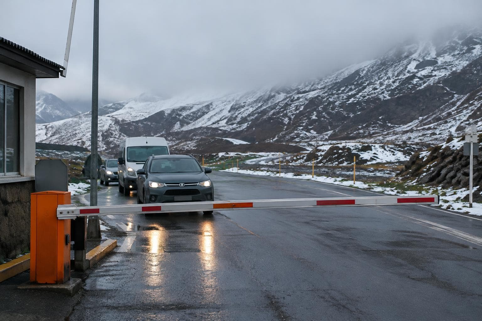 Una barrera baja en una ruta andina nevada, con vehículos esperando.