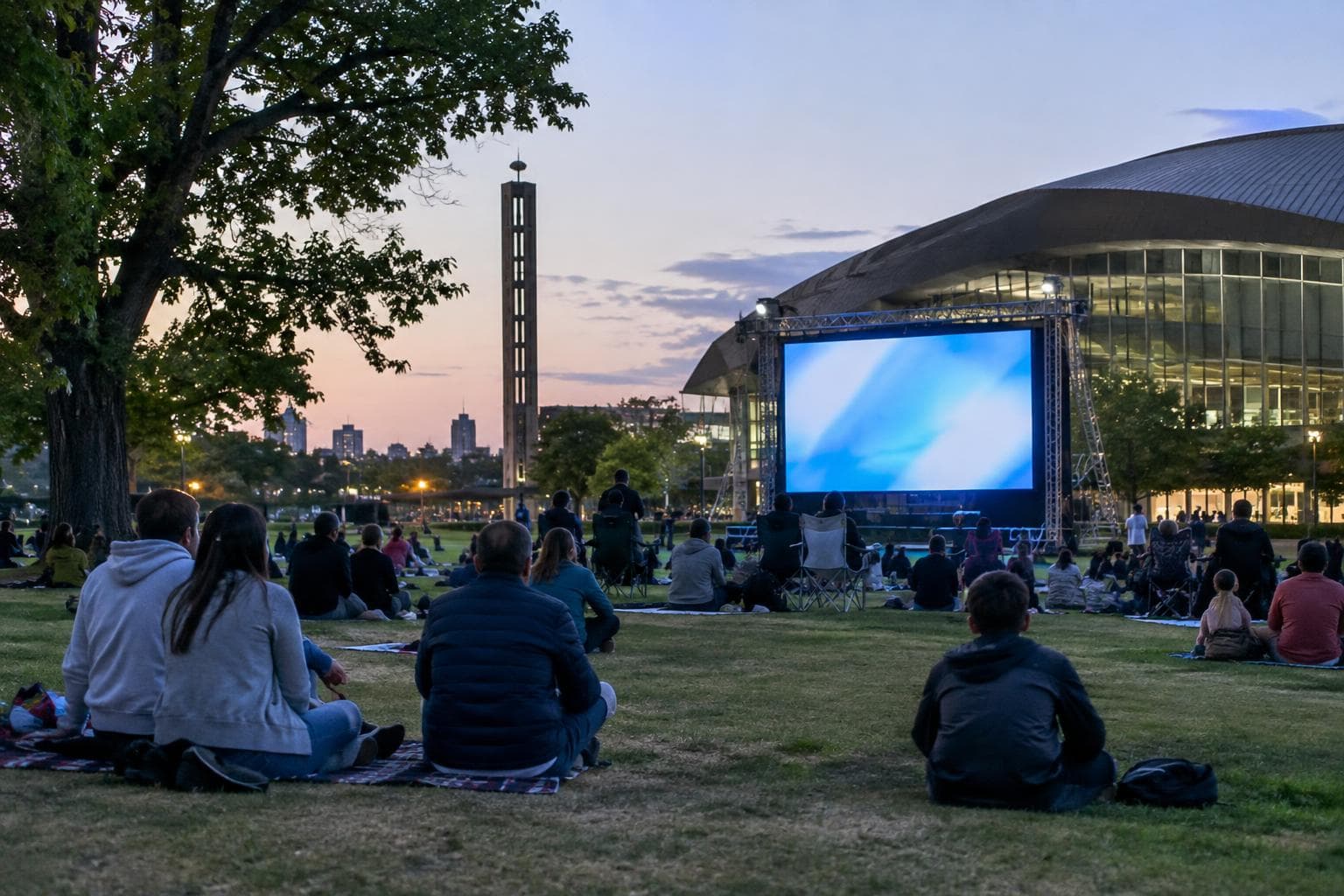 Vecinos reunidos en un parque urbano de Rosario frente a una pantalla gigante, con clima de despedida futbolera.