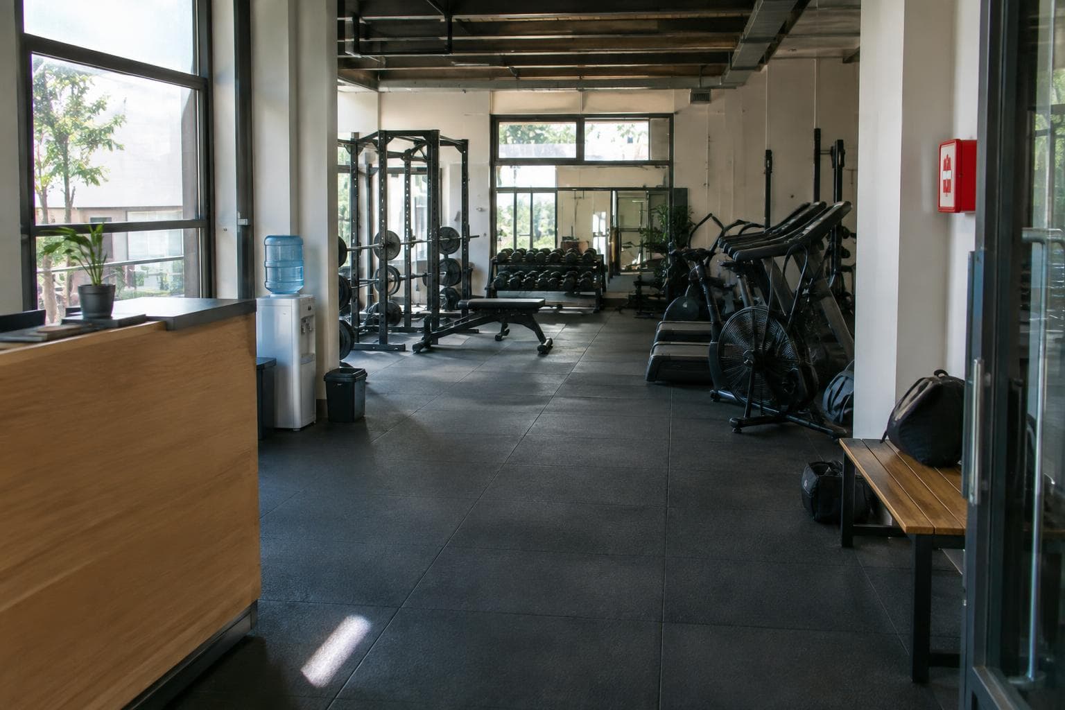 Un gimnasio urbano con máquinas, mostrador y luz natural.