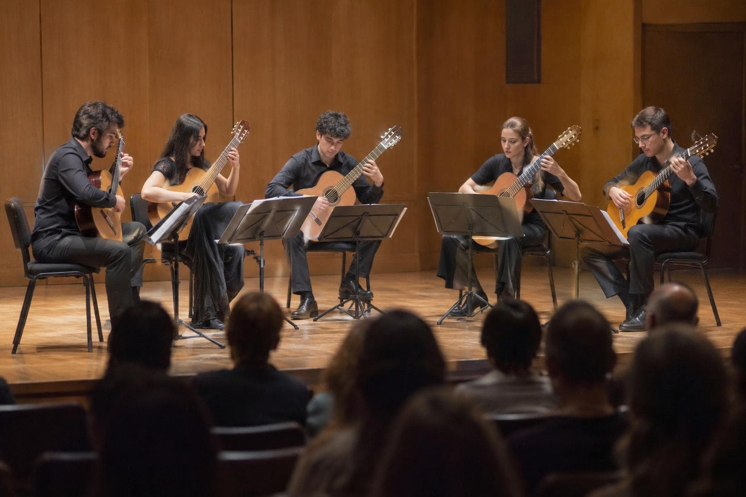 Guitarristas en un auditorio universitario.
